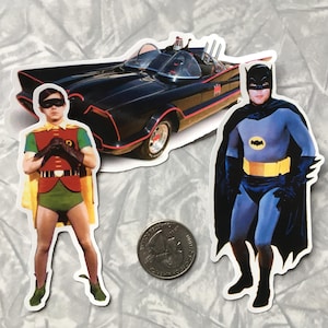 May include: Stickers featuring Batman, Robin, and the Batmobile from the classic TV series. The Batmobile is black with red accents. Robin is in a red, green, and yellow costume. Batman is in a blue and black suit with a yellow belt.