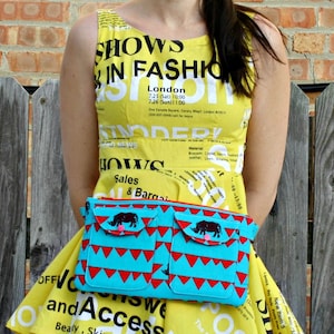 Puede incluir: Un vestido amarillo sin mangas con texto negro y una riñonera turquesa. La riñonera tiene dos bolsillos con triángulos rojos y un diseño de rinoceronte negro. El vestido tiene el texto "SHOWS IN FASHION London".