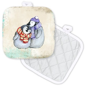 May include: Two penguins wearing scarves and hats stand on a light brown background with a blue and green watercolor wash. The penguin on the left is wearing a red and white scarf and the penguin on the right is wearing a purple and white scarf. The pot holder is white with a quilted pattern.