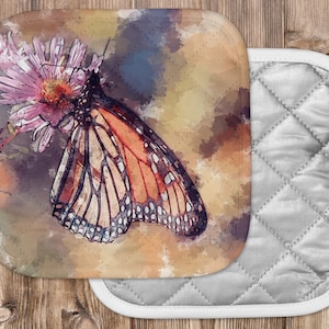 May include: A watercolor painting of a monarch butterfly with orange and black wings perched on a pink flower. The background is a soft watercolor wash of blues, greens, and yellows.