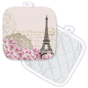 May include: A pink and white pot holder with a quilted back. The front features a vintage postcard design with the Eiffel Tower, pink flowers, and the text "Carte Postale".