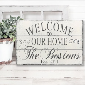 May include: White wooden sign with the text "Welcome to our home The Bostons Est. 2011" in gray lettering.