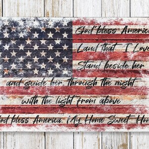 May include: A distressed wood sign with a faded American flag design and the lyrics to the patriotic song "God Bless America". The text reads: "God Bless America, Land That I Love, Stand Beside Her, And Guide Her Through The Night With The Light From Above, God Bless America, My Home Sweet Home."