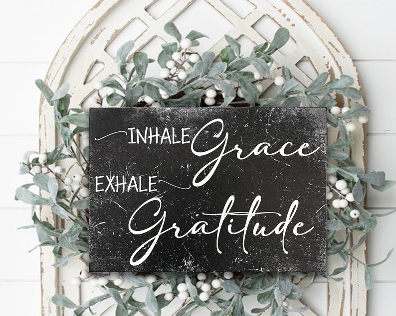 May include: Black wooden sign with white text that reads "Inhale Grace Exhale Gratitude".