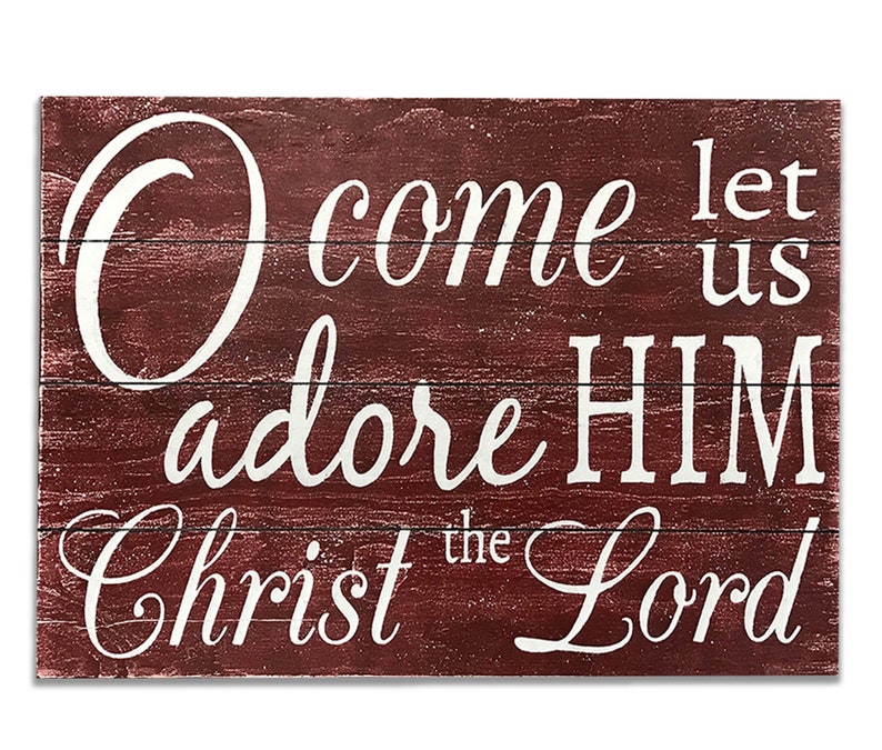 May include: A rustic wooden sign with a red background and white lettering. The sign reads "O come let us adore HIM Christ the Lord".