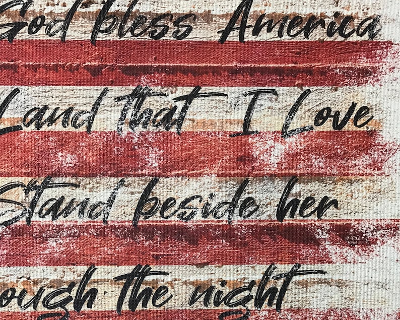 May include: A distressed wood sign with the words "God bless America, land that I love, stand beside her through the night" painted in black on a red, white, and blue American flag background.