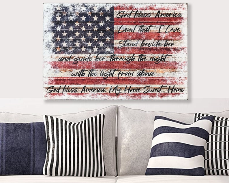 May include: A distressed wood American flag with the words "God Bless America, Land That I Love, Stand Beside Her, And Guide Her Through The Night With The Light From Above, God Bless America My Home Sweet Home" written on it.