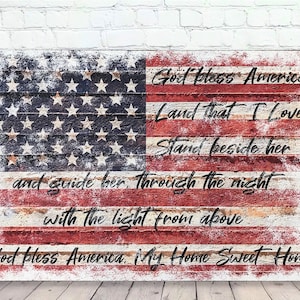 May include: A distressed wood sign with a faded American flag design and the lyrics to the patriotic song "God Bless America". The text reads "God bless America, Land that I love, Stand beside her, and guide her through the night with the light from above, God bless America, My Home Sweet Home."