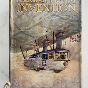 Może przedstawiać: Okładka starej książki zatytułowanej "Triumphs of Invention". Okładka przedstawia ilustrację futurystycznego sterowca z flagą Union Jack. Paleta kolorów obejmuje odcienie niebieskiego, szarego i beżowego, z tytułem w złotych literach.