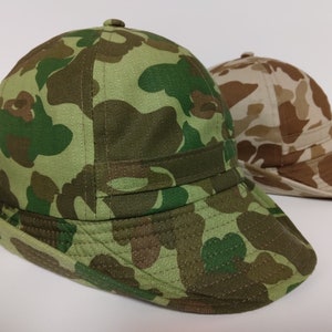 May include: Two camouflage bucket hats. One hat is green and brown camouflage, the other is tan and brown camouflage.