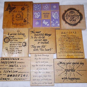 May include: A collection of wooden stamps with various inspirational quotes and designs. The stamps feature phrases like "Happiness is as a butterfly" and "May your special day sparkle." Some stamps have butterfly and floral motifs.