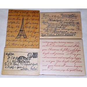 May include: Four wooden stamps with text and illustrations. One features the Eiffel Tower and French text. Another has Russian text. A third stamp has an envelope design and English text. The last stamp has holiday greetings.