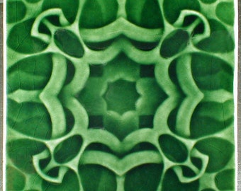 May include: Square ceramic tile with a repeating green pattern. The design features a central star-like shape surrounded by interconnected, organic forms in varying shades of green. The tile has a glossy finish and a slightly cracked appearance.