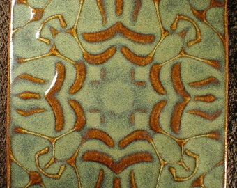 May include: Square ceramic tile with a symmetrical design. The tile has a light green background with a pattern of brown, organic shapes and lines. The edges of the tile are also brown.