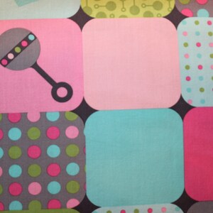 May include: A colorful fabric with a pattern of squares. Each square has a different pattern, including polka dots, stripes, and a rattle. The fabric is perfect for a baby quilt or other sewing projects.