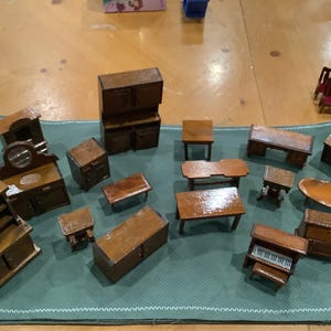 May include: A collection of miniature wooden furniture pieces, including a cabinet, a dresser, a table, a piano, and a chair. The pieces are all made of wood and have a natural finish.
