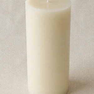 May include: A tall, cylindrical pillar candle in an off-white, cream color. The candle features a smooth, solid wax surface with a single, centered white cotton wick protruding from the flat top. The design is simple, vertical, and uniform.