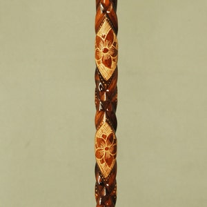 Peut inclure: Canne en bois avec une finition marron foncé. La canne présente un motif torsadé sculpté avec des motifs floraux de couleur marron clair. La tige de la canne mesure environ 91 cm de long.