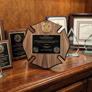 May include: A wooden Maltese cross-shaped plaque featuring a central gold medallion with two crossed American flags. A black metal plate is engraved with text honoring Past Chief Ronald Browne II, including the motto Honor, Pride, Integrity.