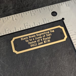 a size example of a brass engraving tag this one measures 2 and 3/4 in left to right and 7/8 of 1 in tall it is shown next to a ruler to confirm the size is accurately depicted in the listing text