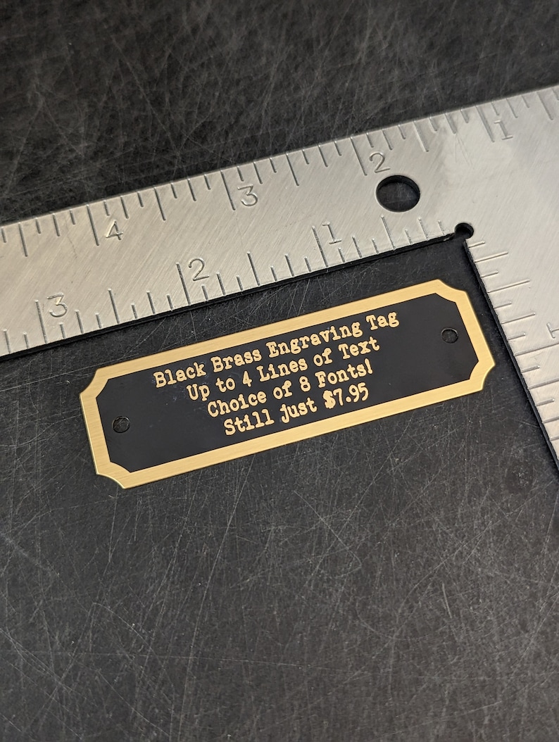 a size example of a brass engraving tag this one measures 2 and 3/4 in left to right and 7/8 of 1 in tall it is shown next to a ruler to confirm the size is accurately depicted in the listing text