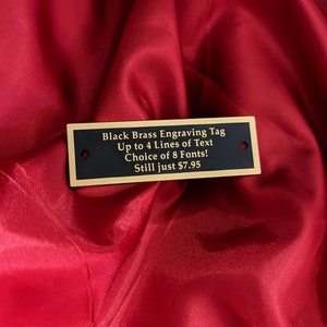 May include: Black brass engraving tag with gold trim. The tag reads "Black Brass Engraving Tag Up to 4 Lines of Text Choice of 8 Fonts! Still just $7.95".