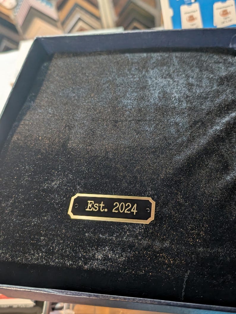a personalized brass engraving plate shown with sample text on a Black Velvet background an example of it being used on a gift item
