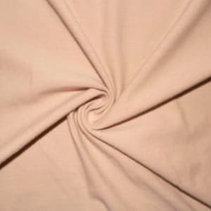 Peut inclure: Gros plan sur un tissu doux de couleur pêche à la texture lisse. Le tissu est plié et drapé, créant un effet fluide et délicat.