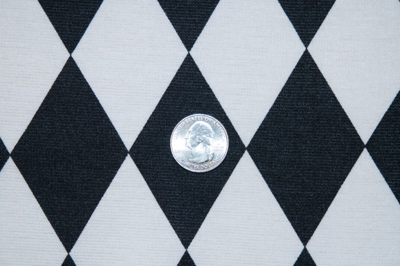 Puede incluir: Una moneda de un cuarto de d&oacute;lar estadounidense de plata sobre una tela con estampado de diamantes negros y blancos.