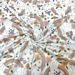 May include: White fabric with a repeating pattern of ghosts wearing witch hats and glasses, rainbows, and flowers in shades of pink, yellow, and orange.
