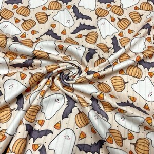 May include: A beige fabric with a repeating pattern of white ghosts, orange pumpkins, and black bats. The pattern also includes small orange and white candy corn.