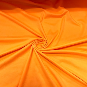 May include: A close-up of a bright orange fabric with a swirling pattern. The fabric is smooth and has a soft texture.