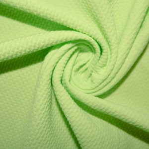 Puede incluir: Primer plano de una tela de punto de waffle verde claro. La tela está doblada y retorcida, mostrando la textura del punto de waffle.
