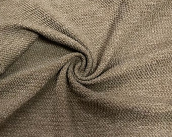 May include: Close-up of a brown waffle knit fabric. The fabric has a textured, waffle-like pattern and a soft, cozy feel.