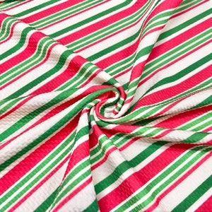 Peut inclure: Tissu ray&eacute; rouge, vert et blanc avec une surface textur&eacute;e. Le tissu est pli&eacute; et tordu, montrant le motif.