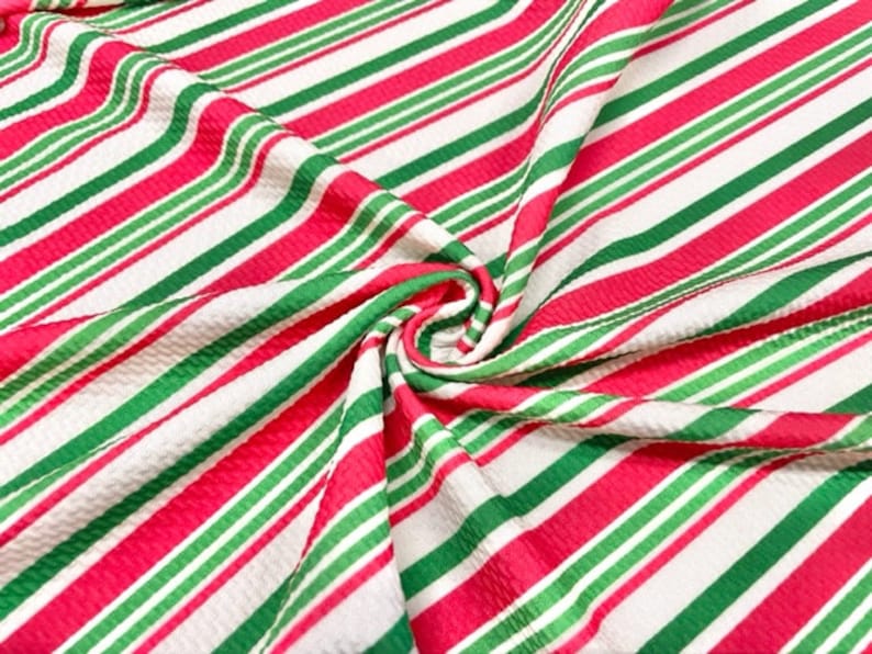 Peut inclure: Tissu ray&eacute; rouge, vert et blanc avec une surface textur&eacute;e. Le tissu est pli&eacute; et tordu, montrant le motif.