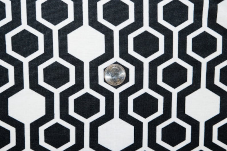 May include: Black and white geometric fabric with a repeating hexagonal pattern. The fabric has a textured surface.
