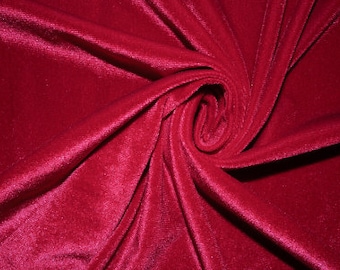May include: A close-up of a deep red velvet fabric, showing the soft texture and rich color. The fabric is draped and folded, creating a luxurious and elegant look.