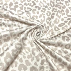 May include: Cream-coloured fabric featuring a leopard print pattern in shades of grey and taupe. The fabric is gathered in a swirl, highlighting the texture and design. Suitable for clothing or home décor.