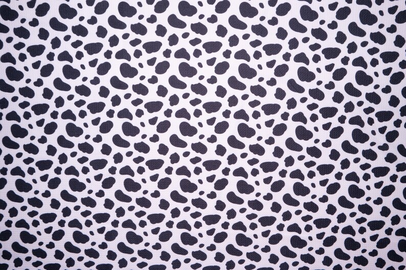 May include: A repeating pattern of black, irregular shapes against a white background. The shapes are reminiscent of animal spots, creating a textured, spotted design. This pattern is suitable for various fabric applications.