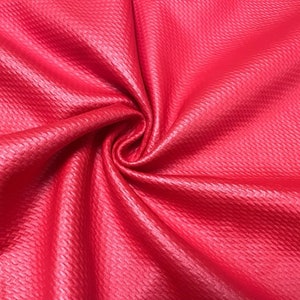 Puede incluir: Tela roja texturizada con un brillo sutil. La tela está doblada y drapeada, mostrando su textura y caída.