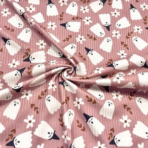 May include: Pink fabric with a white ghost pattern and small white flowers. The ghosts are wearing witch hats.