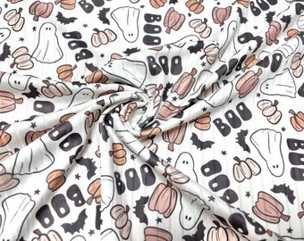 May include: White fabric featuring a repeating Halloween pattern. The design includes ghosts, pumpkins, bats, and the word "BOO" in black. The pumpkins are in shades of peach and brown.