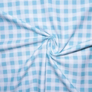 Könnte beinhalten: Nahaufnahme eines Stoffes mit blau-weißem Vichy-Muster. Der Stoff ist in der Mitte gerafft, wodurch weiche Falten und Schatten entstehen. Das Muster besteht aus gleichmäßig verteilten Quadraten und erzeugt ein klassisches und vielseitiges Design.