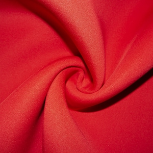 May include: Close-up of a bright red fabric with a smooth, even texture. The fabric is folded and draped, creating soft, flowing curves.
