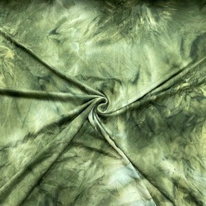 May include: Green and white tie-dye fabric with a swirling pattern. The fabric is soft and stretchy, making it perfect for a variety of projects.