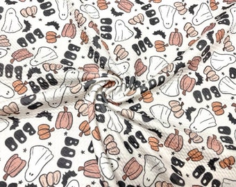 May include: Cream-coloured fabric featuring a Halloween-themed pattern. The design includes ghosts, pumpkins, bats, and the word "BOO" in black. The pumpkins are in shades of orange and peach, with black accents.