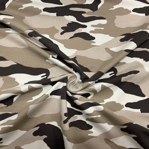 May include: A close-up of a beige, brown, and black camouflage fabric. The fabric is folded and has a soft, textured feel.