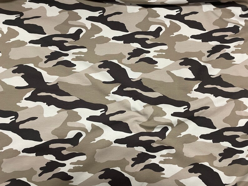 May include: A close-up of a fabric with a camouflage pattern in shades of brown, black, and white.