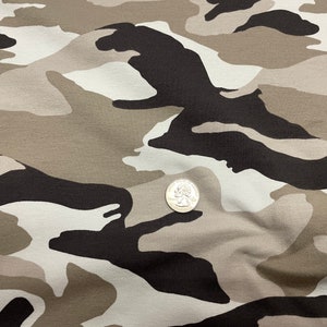 May include: Close-up of a camouflage fabric with a brown, white, and black pattern. A US quarter is placed on the fabric for scale.